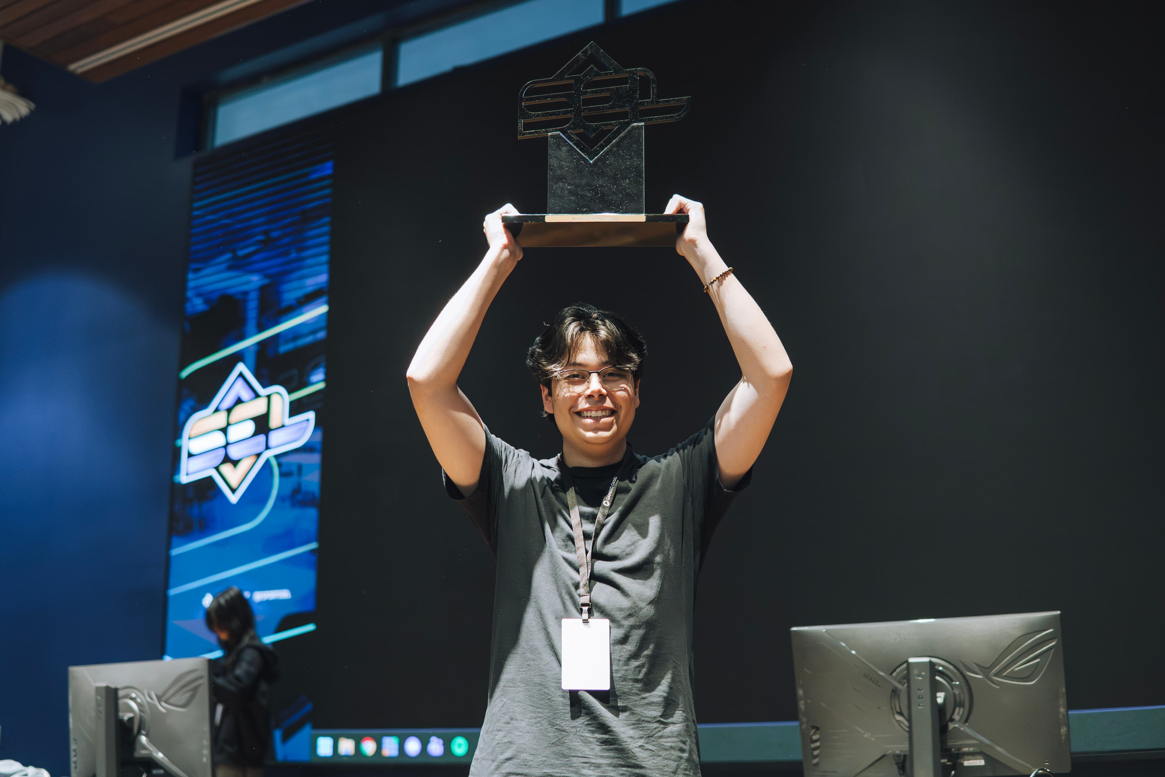 SEL competitor celebrates with a championship trophy on stage